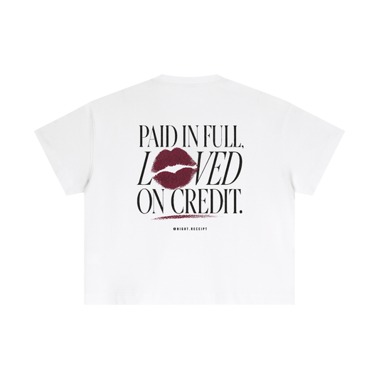 Back of the white Night Receipt boxy cotton tee with PAID IN FULL, LOVED ON CREDIT in editorial serif capitals and a smudged oxblood lipstick print replacing the O in LOVED, smearing into the line below