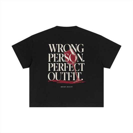 Back of the black Night Receipt boxy cotton tee with WRONG PERSON. PERFECT OUTFIT. in editorial serif capitals and a tipped oxblood wine glass whose spill becomes the baseline