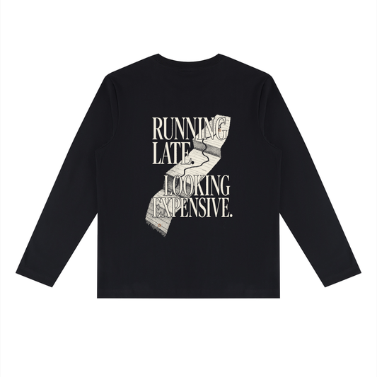 Back of the black heavyweight long sleeve tee with RUNNING LATE. LOOKING EXPENSIVE. in cream editorial serif capitals over a torn receipt-road graphic