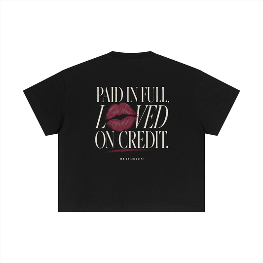 Back of the black Night Receipt boxy cotton tee with PAID IN FULL, LOVED ON CREDIT in editorial serif capitals and a smudged oxblood lipstick print replacing the O in LOVED, smearing into the line below