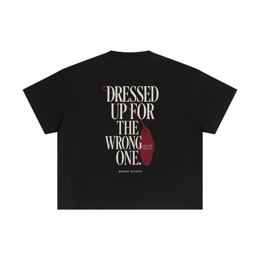 Back of the black Night Receipt boxy cotton tee with DRESSED UP FOR THE WRONG ONE in editorial serif capitals and an unbranded oxblood hotel key tag stamped 02:17 hanging off the type