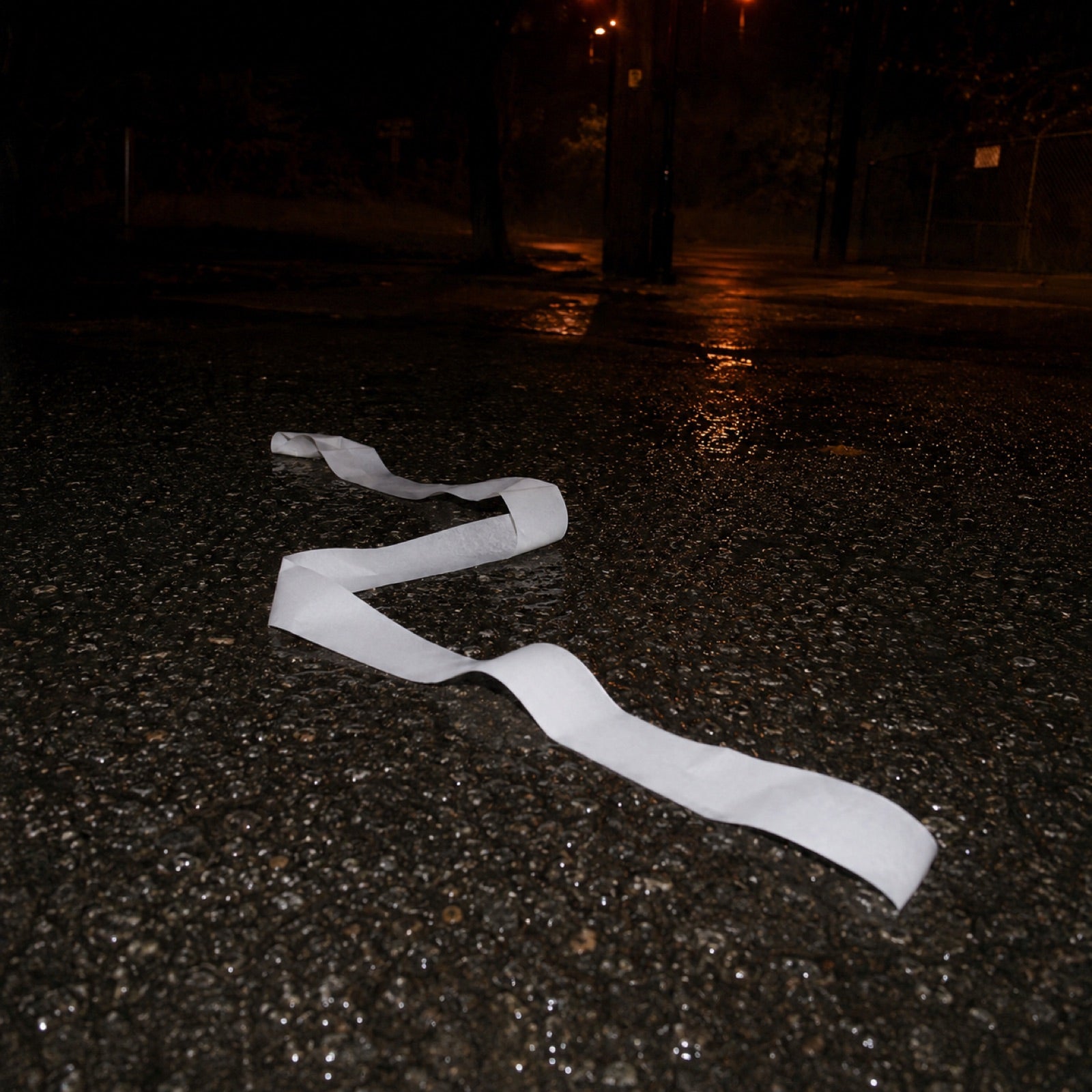 A thermal receipt unrolled across wet asphalt at night